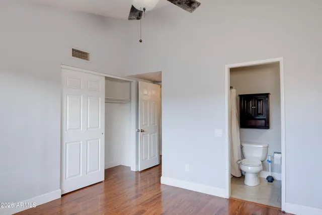 a view of an empty room with wooden floor and a bathroom