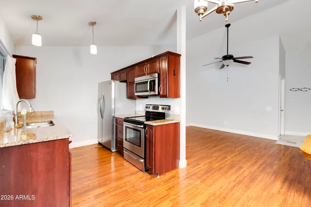 a kitchen with stainless steel appliances granite countertop a sink a stove and a wooden floor