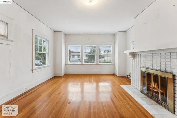 an empty room with windows a fireplace and wooden floor