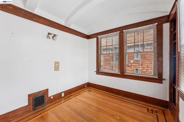 a view of an empty room with a window and wooden floor
