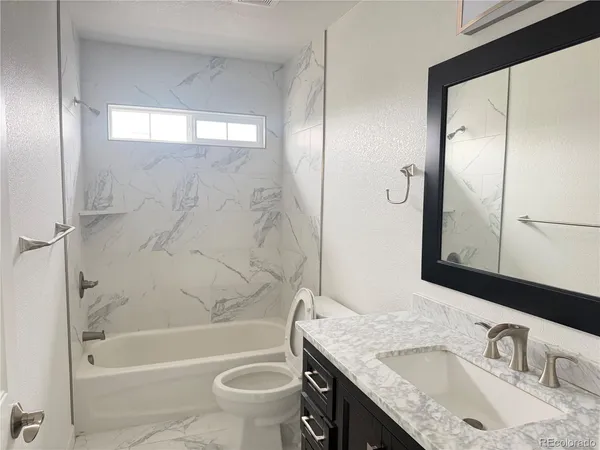 a bathroom with a granite countertop sink toilet and shower