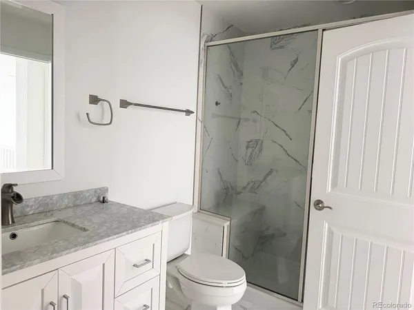 a bathroom with a granite countertop sink toilet and shower
