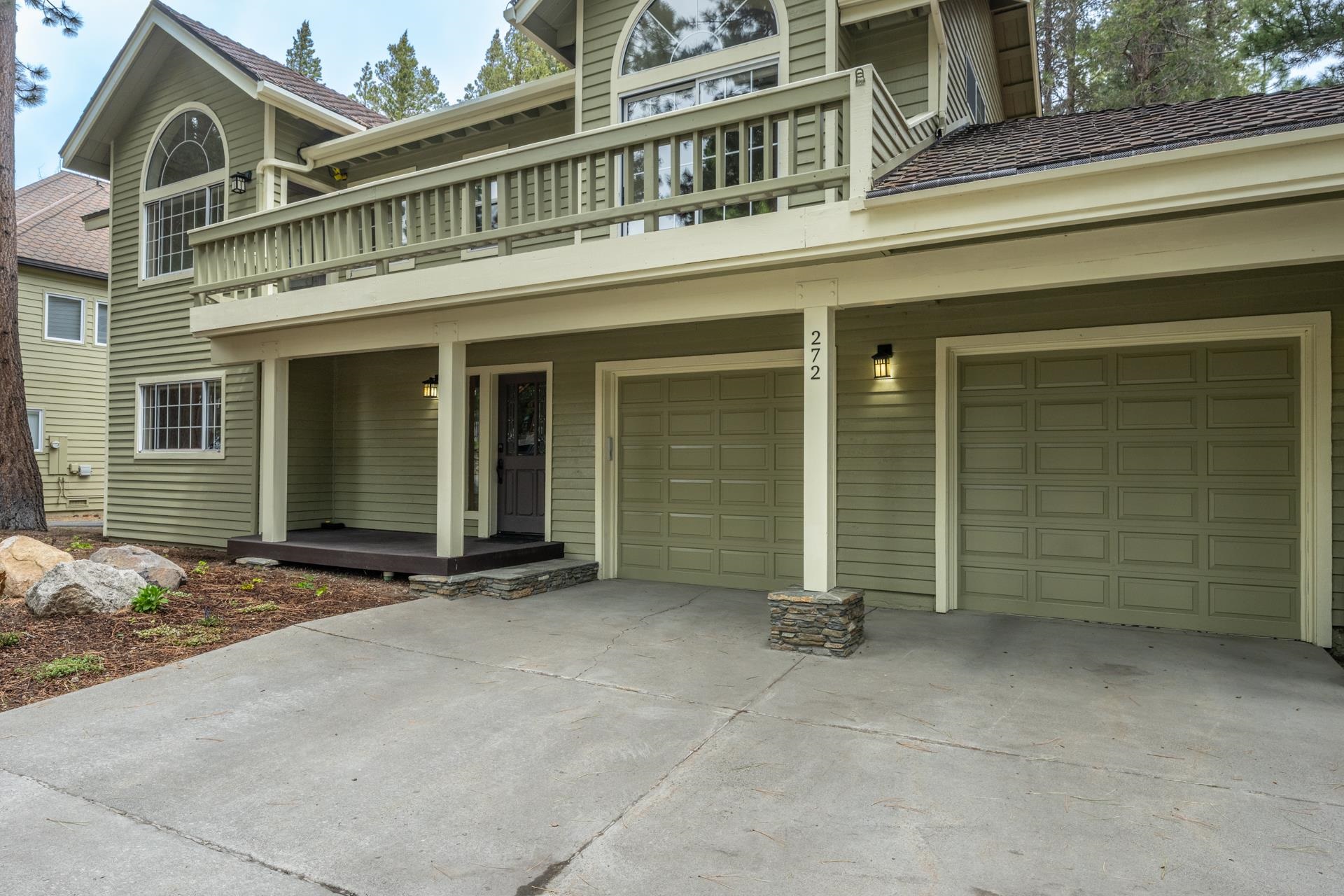 272 Ridge Way Mammoth Lakes, CA 93546 - Photo 7 of 55 Two-car garage with panel doors, upper-level balcony, arched window, and stone column detailing