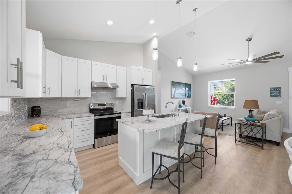 10443 Riverside Road Port Charlotte, FL 33981 - Photo 12 of 64 a kitchen with stainless steel appliances kitchen island granite countertop a stove a sink a dining table and chairs