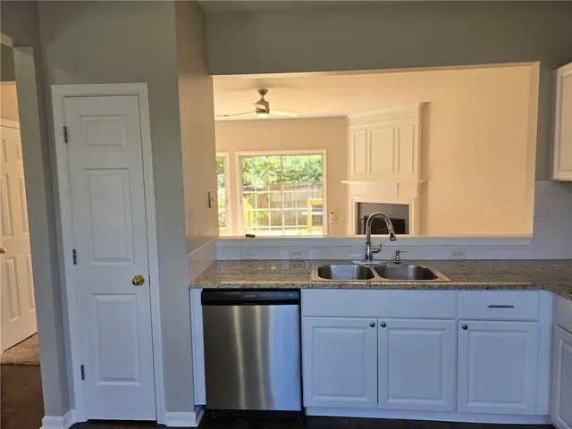 a kitchen with granite countertop white cabinets and sink