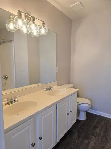 a bathroom with a granite countertop sink a toilet and a mirror
