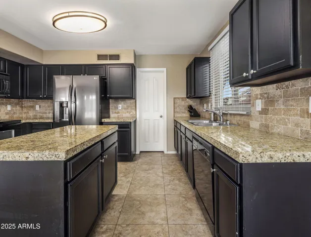 a kitchen with stainless steel appliances granite countertop a refrigerator a stove and a sink with wooden floor