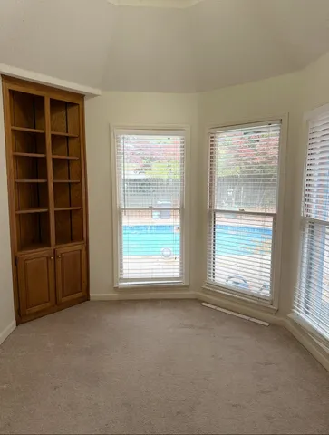 a view of an empty room with a window and cabinet