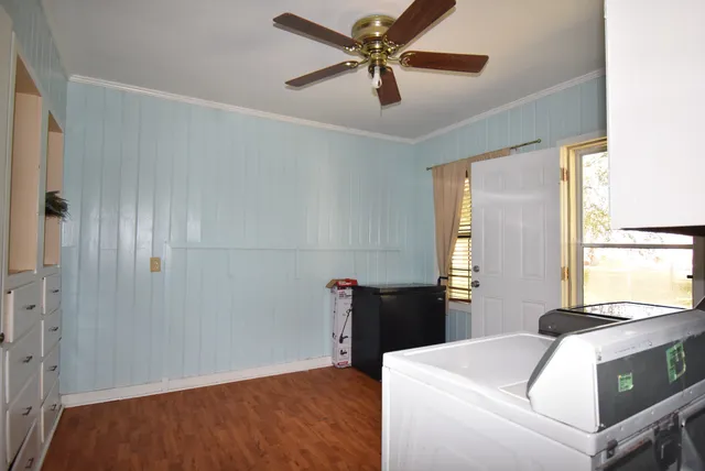 an empty room with wooden floor fan and windows