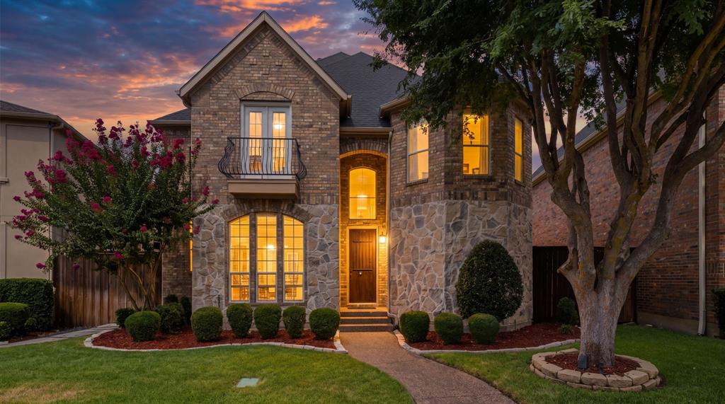 3315 Ricci Lane Irving, TX 75062 - Photo 1 of 40 Brick and stone exterior featuring an arched entryway, decorative balcony, and a manicured lawn with mature trees