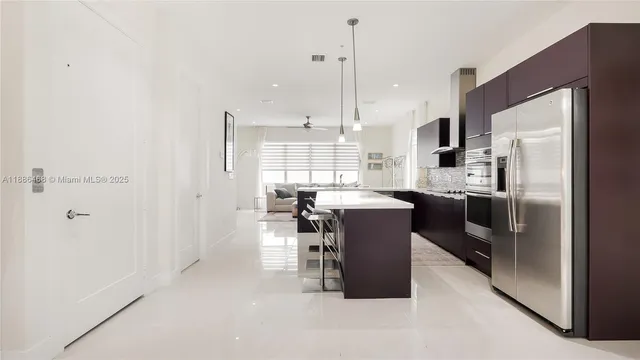 a kitchen with a refrigerator a stove a sink and a dining table with wooden floor