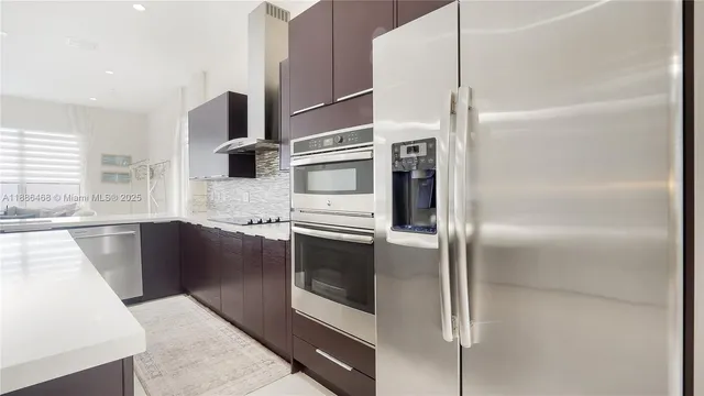 a kitchen with stainless steel appliances kitchen island granite countertop a refrigerator and a sink