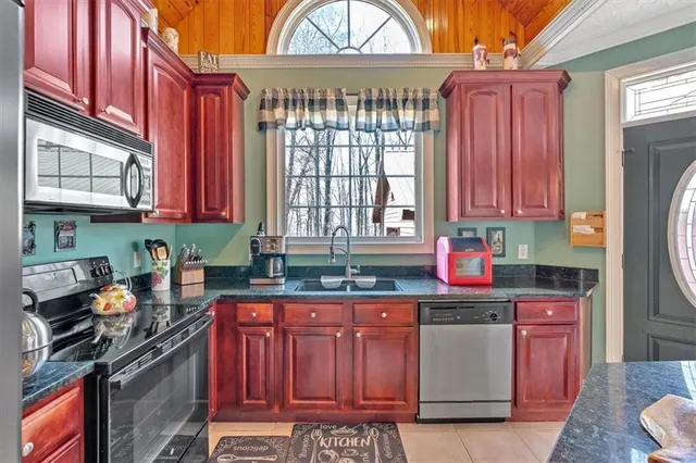 a kitchen with stainless steel appliances granite countertop a stove top oven a sink dishwasher and cabinets with wooden floor