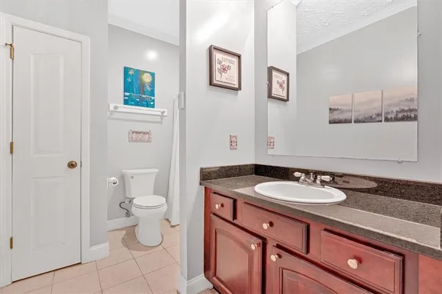 a bathroom with a granite countertop sink toilet and painting on the wall