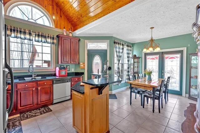 a dining hall with stainless steel appliances granite countertop a stove a sink a oven with a dining table and chairs