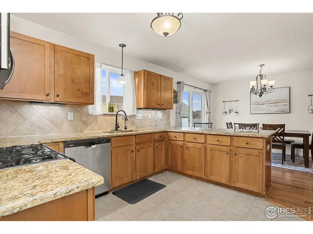 a kitchen with stainless steel appliances kitchen island granite countertop a refrigerator a stove a sink a dining table and chairs with wooden floor