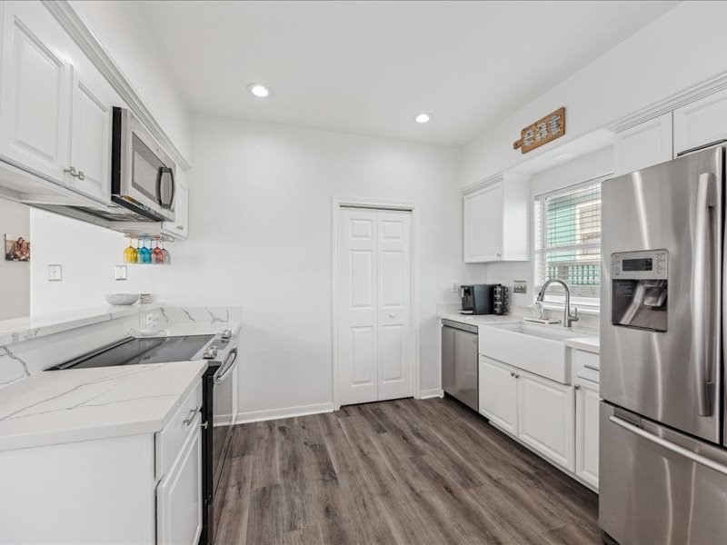 530 Dolphin Street Freeport, TX 77541 - Photo 10 of 29 a kitchen with a sink a refrigerator a stove and white cabinets