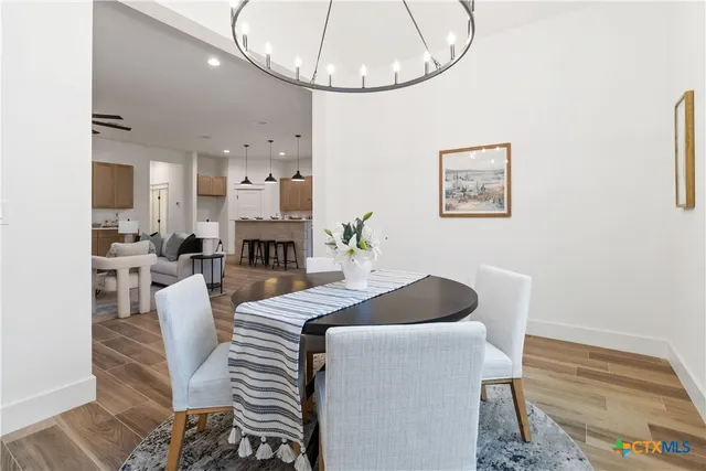 a kitchen with stainless steel appliances granite countertop a stove top oven a sink dishwasher and a dining table with wooden floor