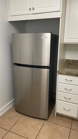 a view of a refrigerator in kitchen and white cabinets