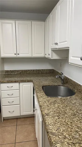 a kitchen with granite countertop white cabinets and sink