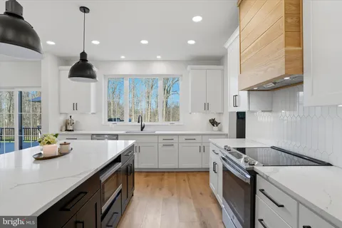 a large kitchen with stainless steel appliances granite countertop a sink a stove and a refrigerator