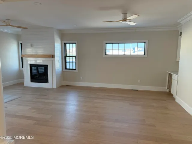 a view of an empty room with wooden floor fireplace and a window
