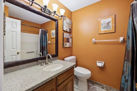 a bathroom with a granite countertop toilet sink and mirror