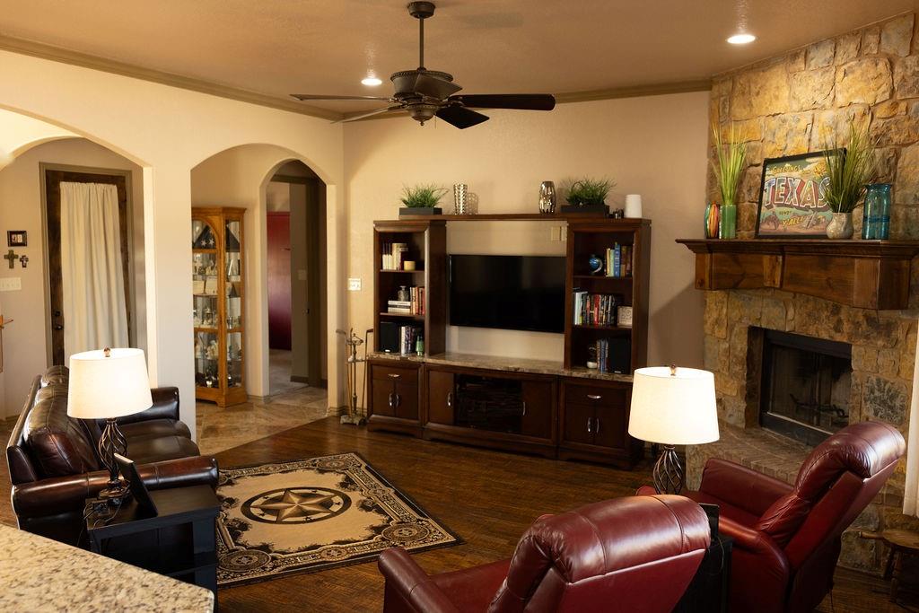 123 Cactus Drive Decatur, TX 76234 - Photo 7 of 30 Stone-faced fireplace with a wood mantel, dark wood-finish flooring, recessed lighting, ceiling fan, and built-in entertainment center