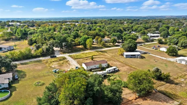 an aerial view of a residential houses with outdoor space and trees all around