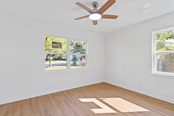 an empty room with a window and ceiling fan