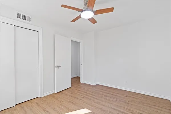 an empty room with wooden floor a ceiling fan and closet