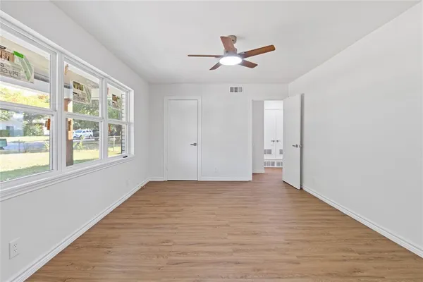 a view of an empty room with a window and wooden floor