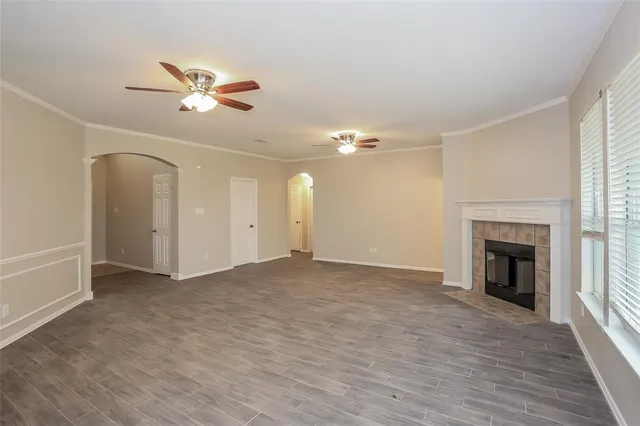 a view of an empty room with chandelier fan and fire place