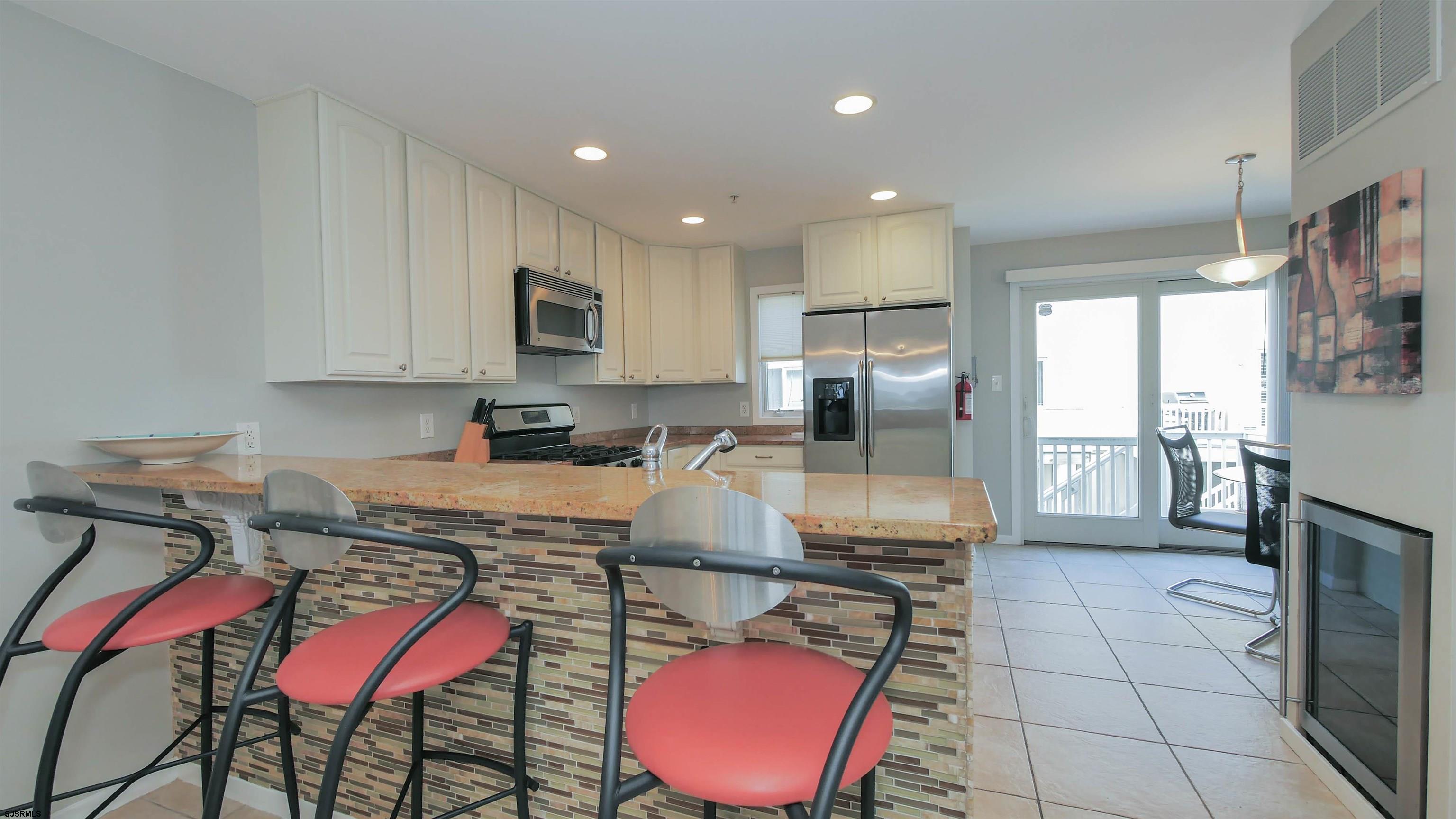 137 South Berkley Square, Unit B Atlantic City, NJ 08401 - Photo 16 of 42 a kitchen with stainless steel appliances granite countertop a stove a sink a microwave a refrigerator and chairs