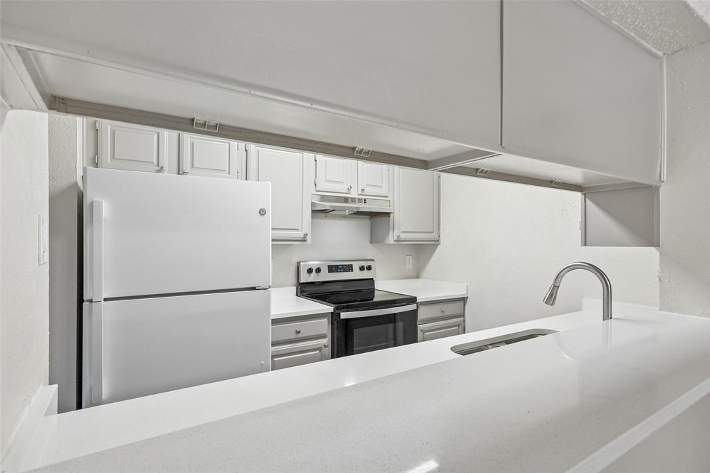 11480 Audelia Road, Unit 136 Dallas, TX 75243 - Photo 21 of 29 Kitchen featuring a pass-through window with a breakfast bar, white cabinetry, light countertops, an electric range, and a white refrigerator