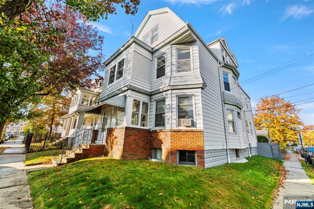 a view of a white house next to a yard with big trees