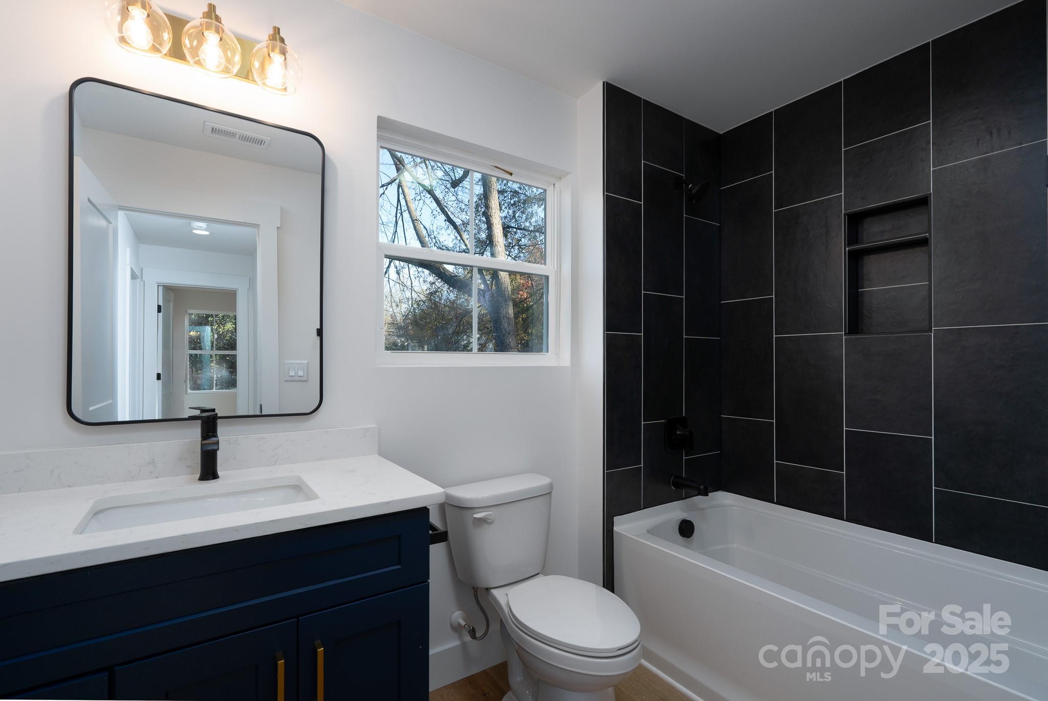 924 Oregon Street Kannapolis, NC 28083 - Photo 3 of 34 a bathroom with a toilet a sink a shower and mirror