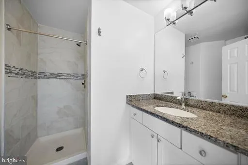 a bathroom with a granite countertop shower sink and mirror