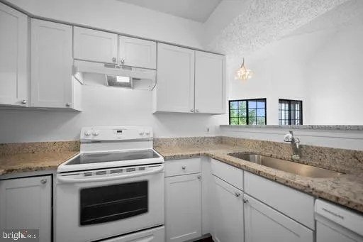 a kitchen with granite countertop white cabinets and white appliances