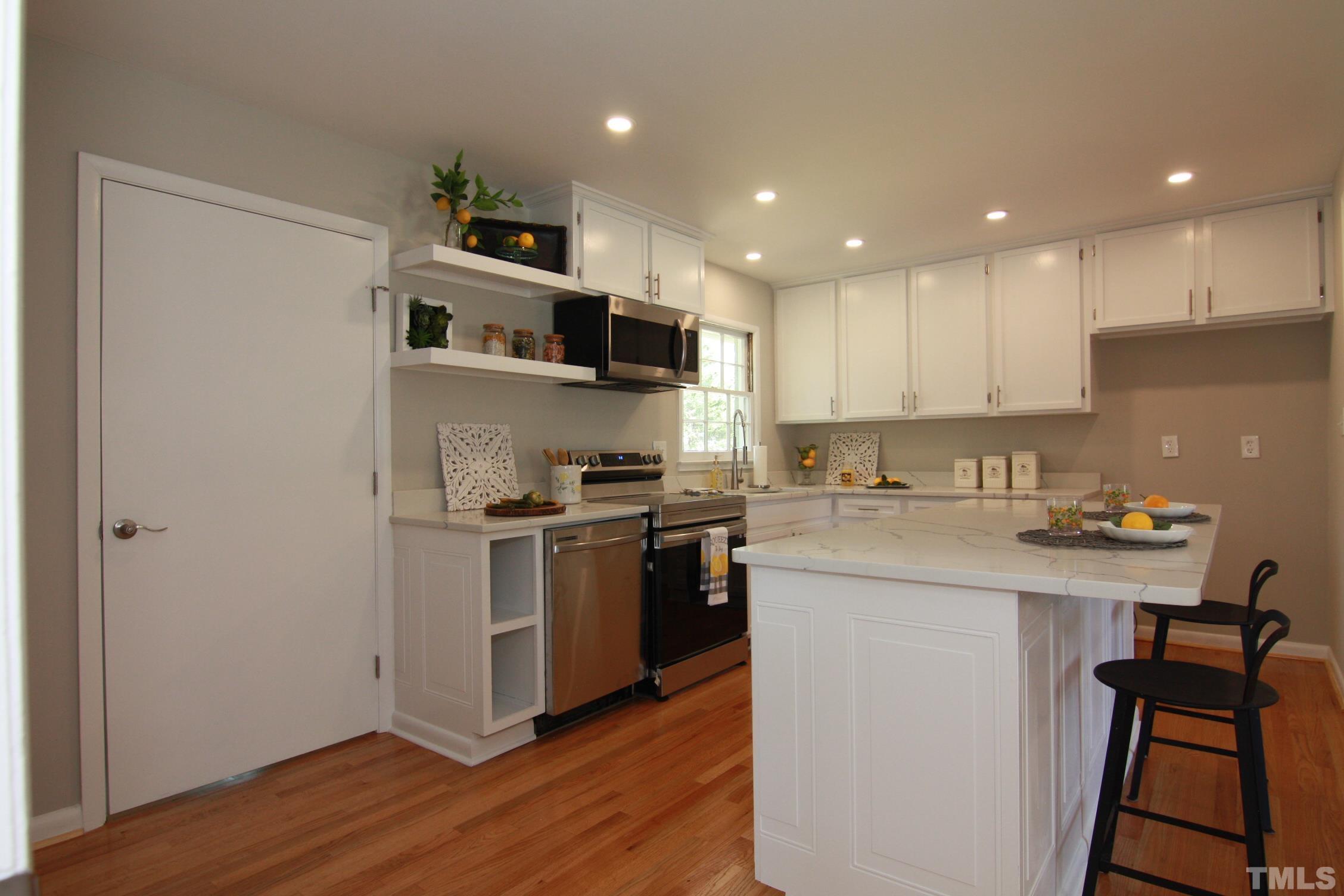 1503 Sedwick Road Durham, NC 27713 - Photo 11 of 33 a kitchen with stainless steel appliances granite countertop a stove top oven a sink and white cabinets