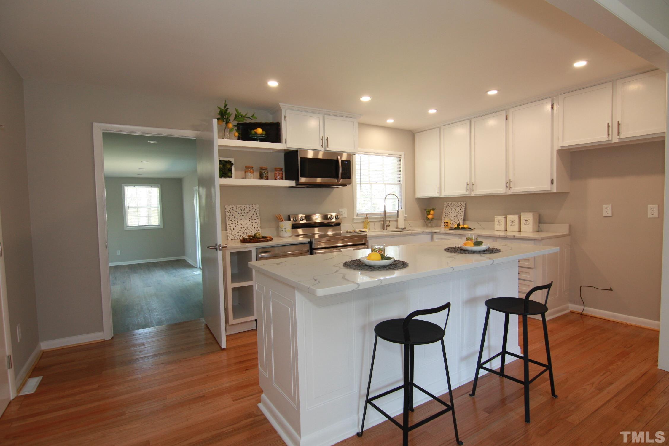 1503 Sedwick Road Durham, NC 27713 - Photo 12 of 33 a kitchen with a sink a refrigerator and wooden floor