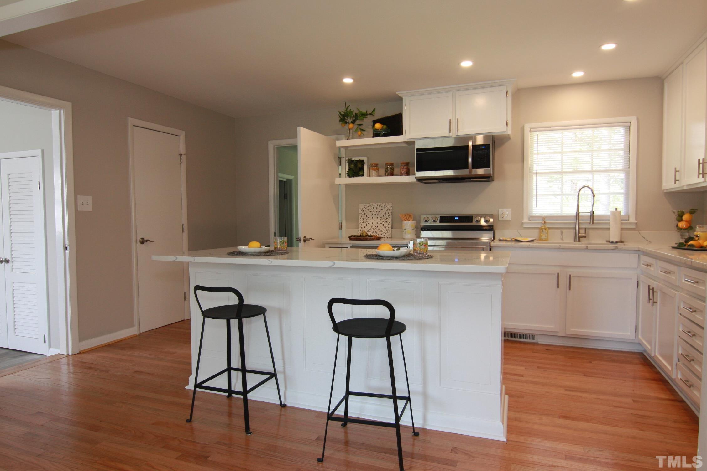 1503 Sedwick Road Durham, NC 27713 - Photo 10 of 33 a kitchen with stainless steel appliances granite countertop a stove top oven a sink dishwasher and white cabinets with wooden floor