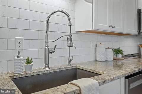 a kitchen with stainless steel appliances granite countertop a stove top oven a sink dishwasher and white cabinets with wooden floor