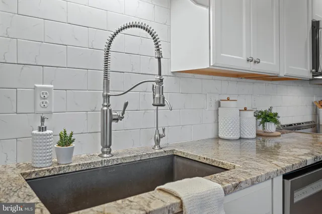 a kitchen with stainless steel appliances granite countertop a stove top oven a sink dishwasher and white cabinets with wooden floor