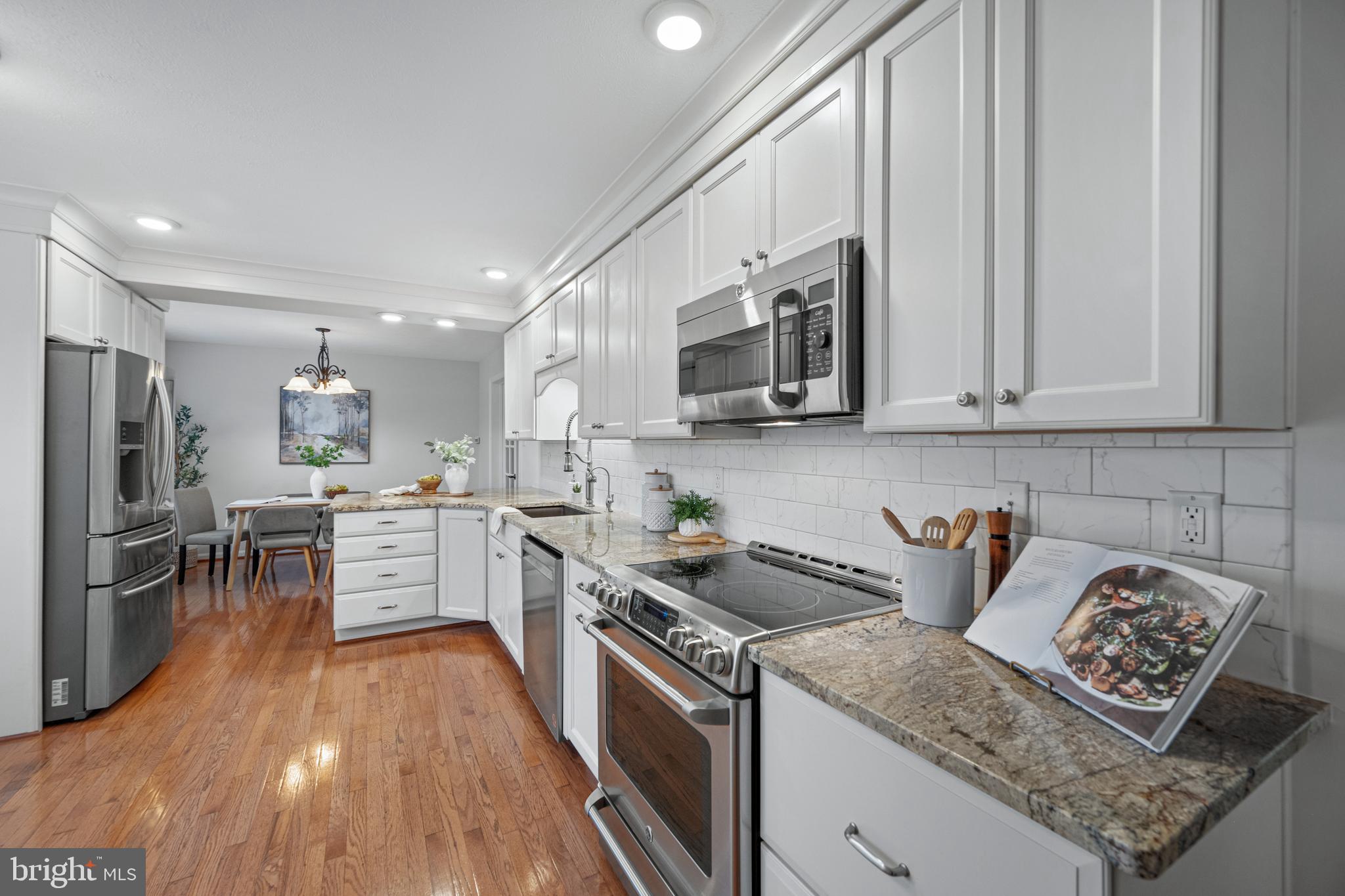 3211 Hayloft Court Woodbine, MD 21797 - Photo 14 of 69 a kitchen with stainless steel appliances granite countertop a stove top oven a sink dishwasher and white cabinets with wooden floor
