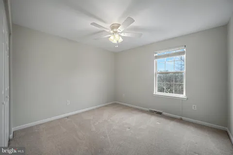 an empty room with a chandelier fan and windows