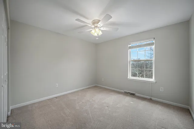 an empty room with a chandelier fan and windows