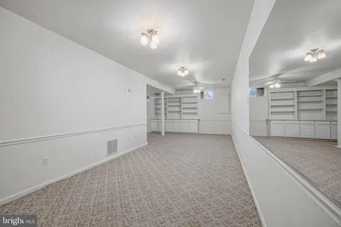 en empty room with white walls and chandelier fan