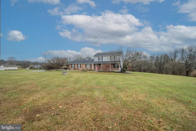 a view of a big house with a big yard and large trees