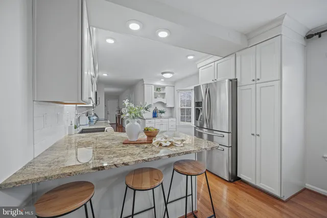 a kitchen with refrigerator a sink and chairs